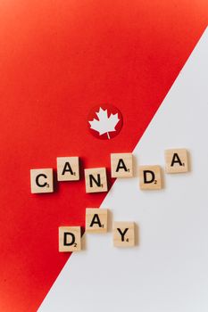 Scrabble tiles spelling 'Canada Day' on a red and white background with a maple leaf.