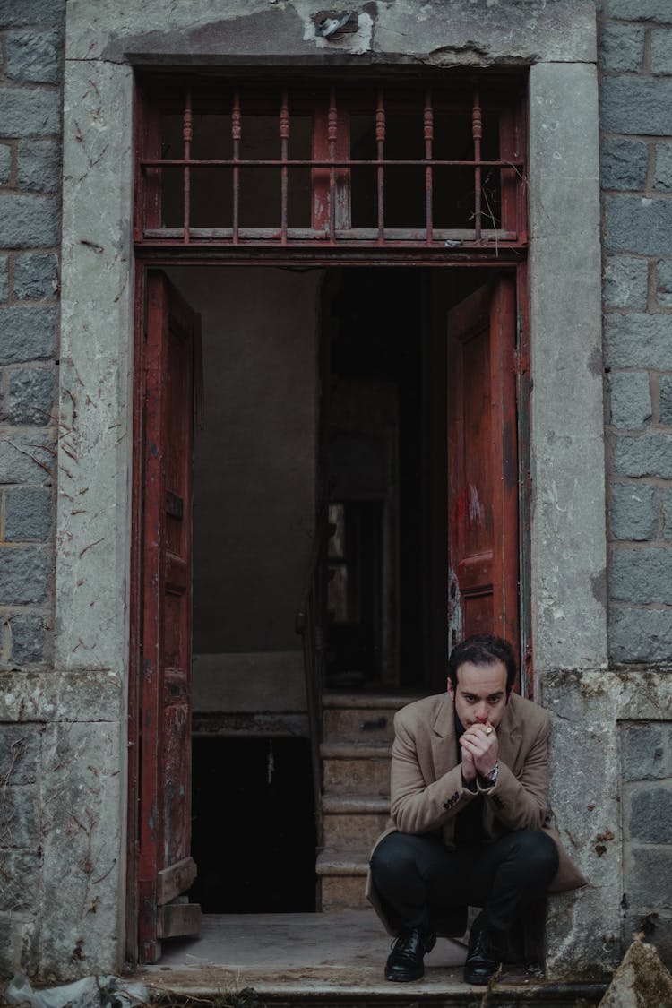 Bankrupt Man Sitting At Entrance Of Damaged Building