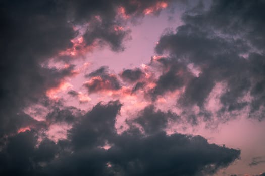 A stunning view of pink and gray clouds in a dramatic sunset sky, creating a moody atmosphere.