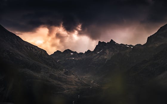 A stunning view of dark clouds over the rugged peak of the Austrian Alps at twilight.