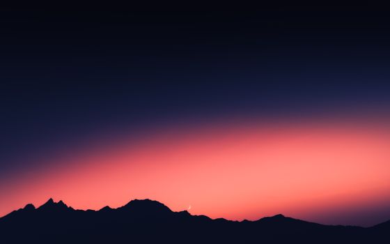 A beautiful silhouette of the Swiss mountains at dawn with a dramatic sky in twilight hues.