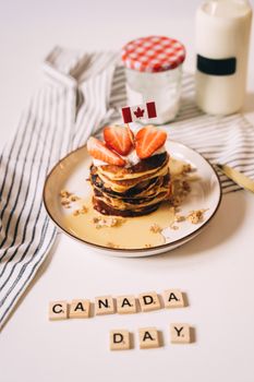 Celebrate Canada Day with delicious pancakes topped with strawberries and maple syrup.