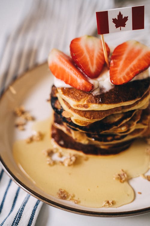 Free Close-Up Photo of a Stack of Pancakes with a Canadian Flag on Top Stock Photo