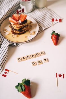 Delicious pancakes with strawberries and Canadian flags celebrating Canada Day.