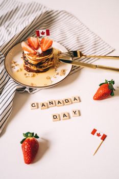Delicious pancakes topped with strawberries and Canadian flags, perfect for Canada Day celebrations.
