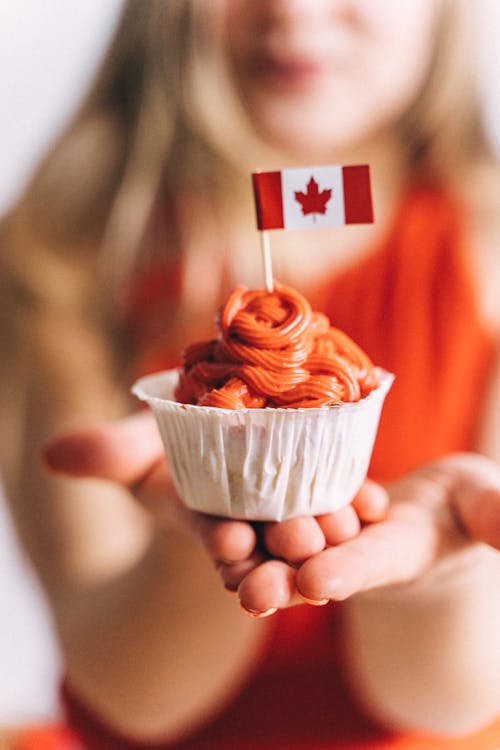 Close-Up Shot of Person Holding a Cupcake with Canadian Flag