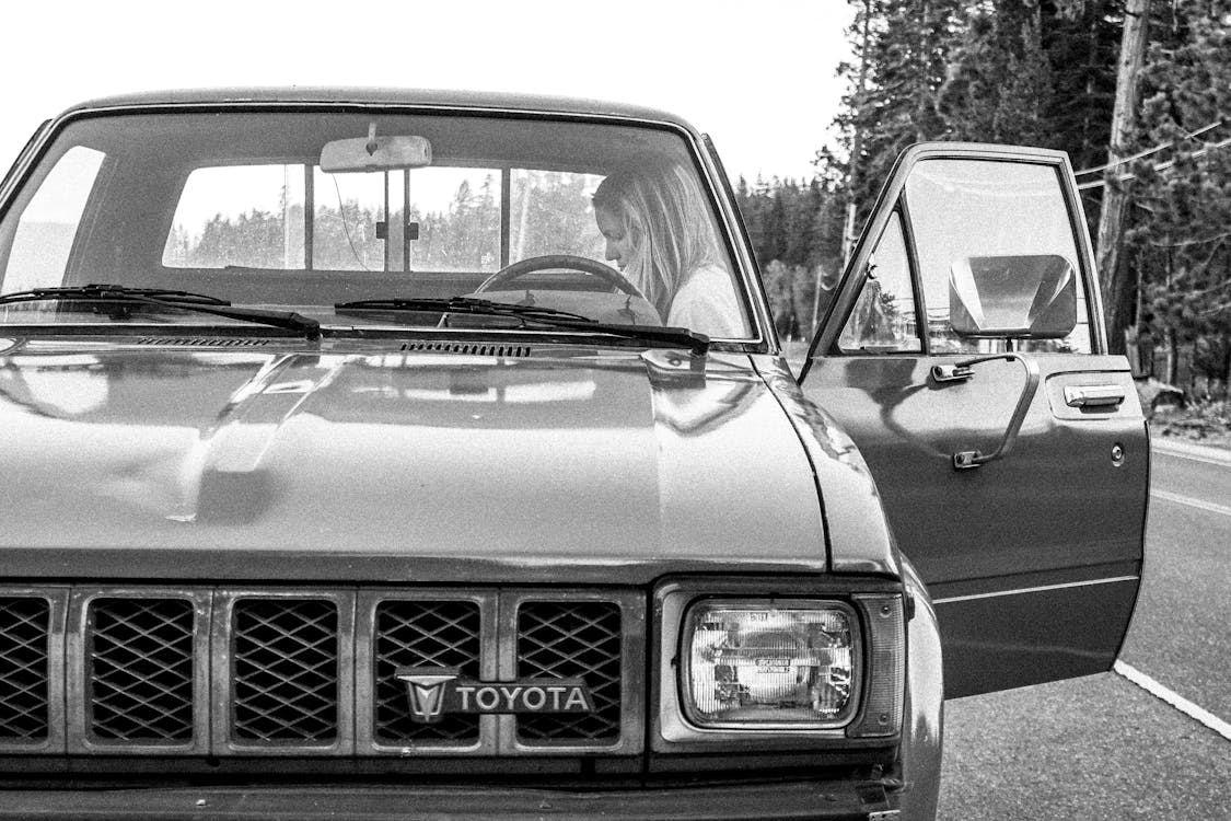 Grayscale Photo of a Woman in a Toyota Car