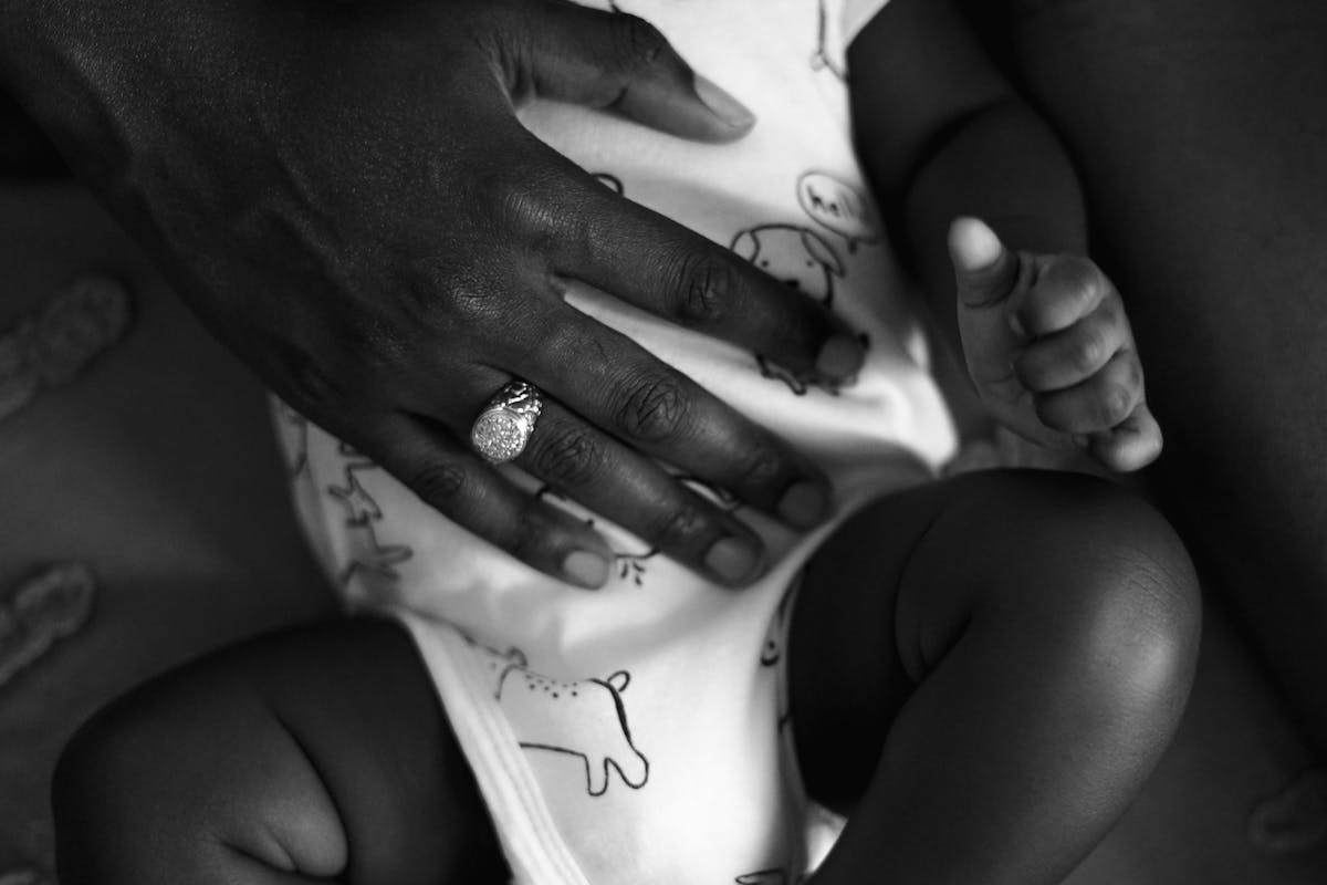 Mano di donna appoggiata delicatamente sull'addome di un neonato