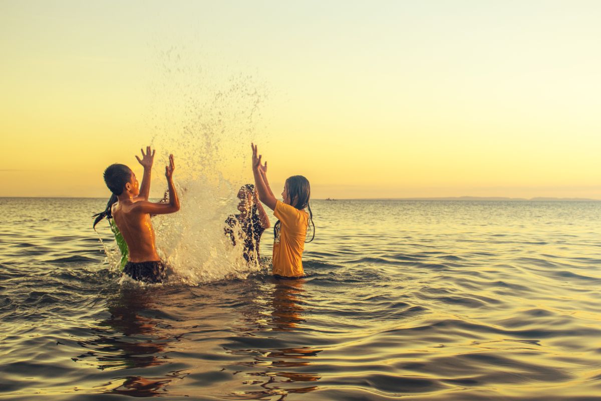 Kids splashing in the lake at sunset