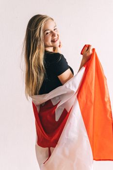 Blonde woman smiling, wrapped in a Canadian flag indoors.