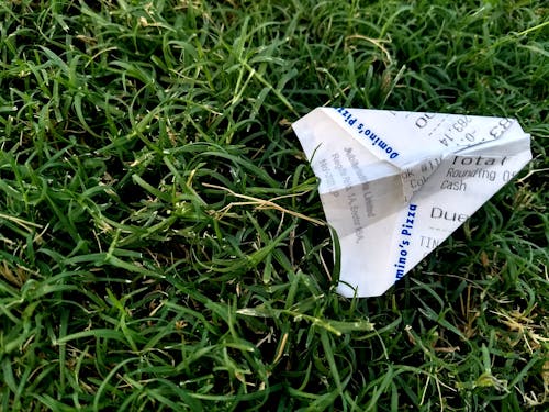 草の上の紙飛行機に折りたたまれた領収書