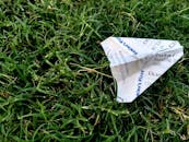 Receipt Folded Into Paper Plane on Grass