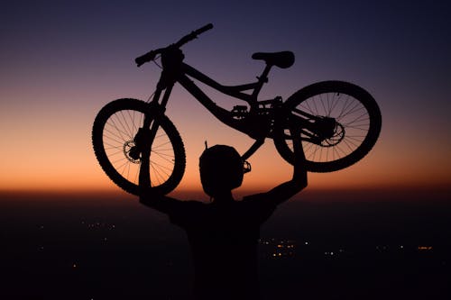 Silhouette of a Person Lifting His Bicycle