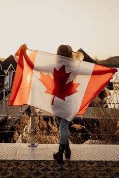 A woman holds a Canadian flag during the day in Toronto, symbolizing national pride and unity.