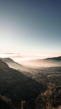 Breathtaking view of a mist-covered mountain valley at sunrise, capturing nature's serene beauty.