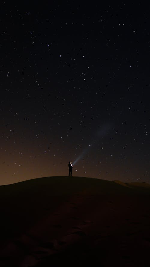 Free Silhouette of a Person Standing on a Hill Under Night Sky Stock Photo