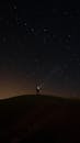 Silhouette of a Person Standing on a Hill Under Night Sky