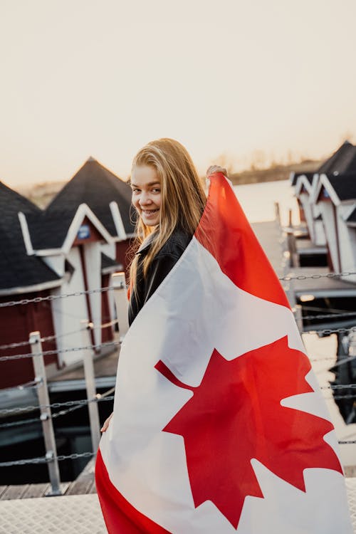 A Woman Wrapped with Canadian Flag while Smiling at the Camera