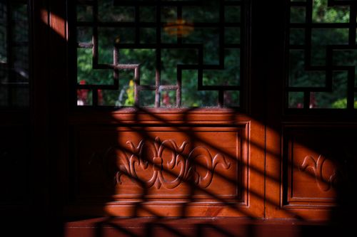 Free Sunlit wooden Chinese window casting intricate shadows indoors. Stock Photo