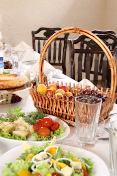 A beautifully arranged dining table with a wicker basket of fruit and fresh salads, ideal for brunch or dinner settings.