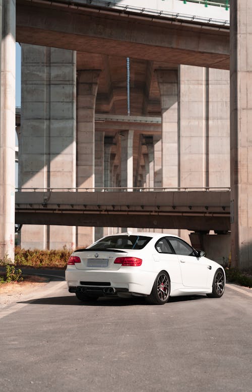 Back View Shot of a White Car Parked Near a Concrete Structure