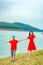 A Couple Standing on the Grass Field Near a Lake while Holding Each Others Hand