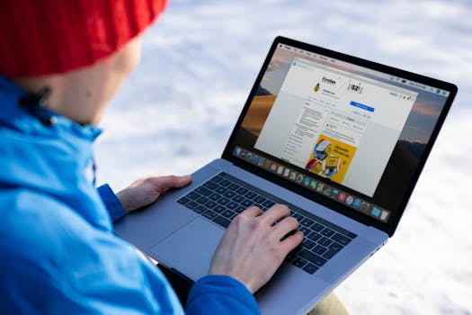 Close-up of individual using laptop outdoors in snow, browsing social media.