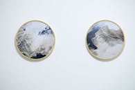 白色墙上挂着两幅金色框架的抽象圆形画作，展现了现代极简主义设计