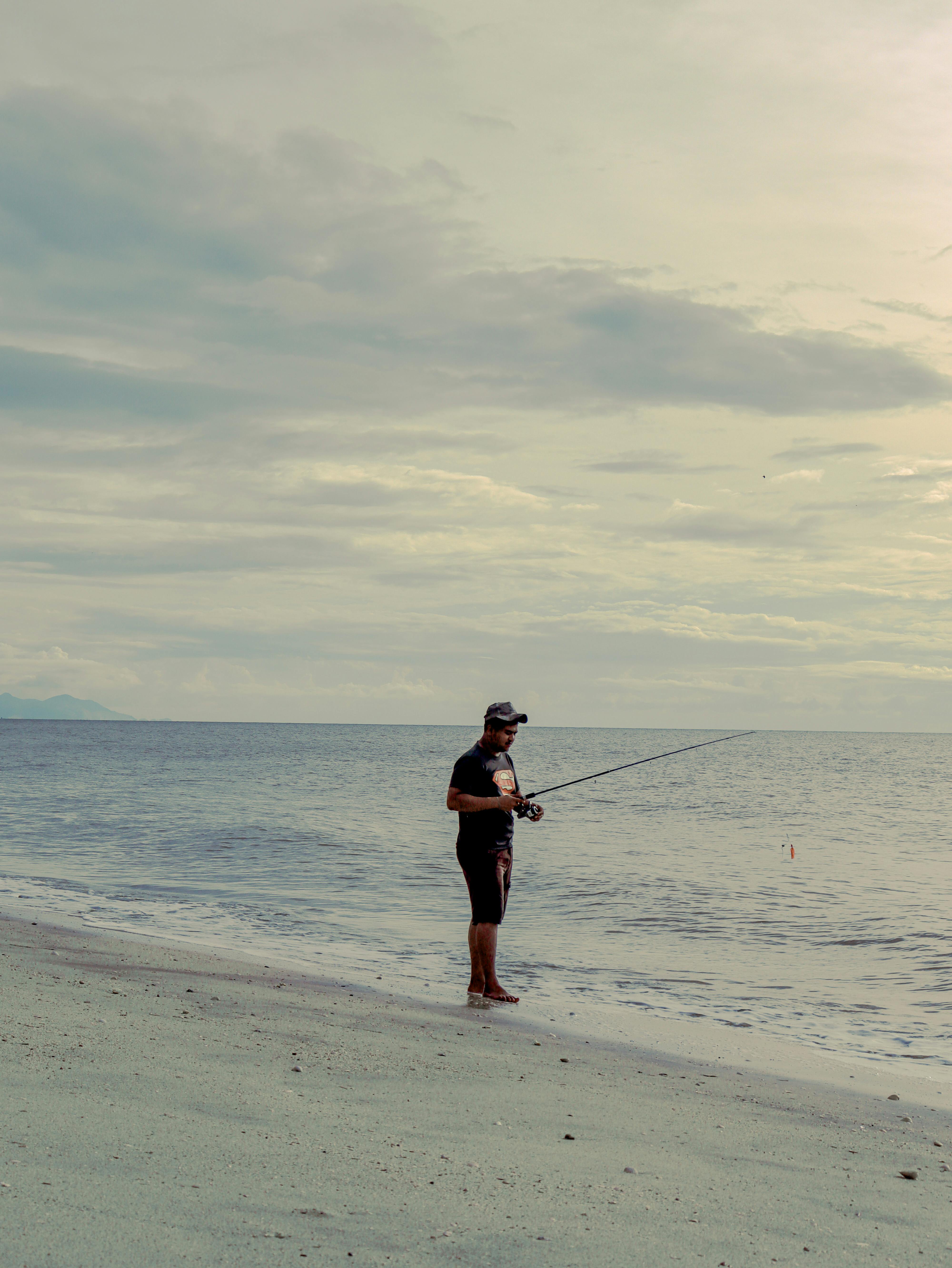A Man Holding a Fishing Rod on the Beach · Free Stock Photo