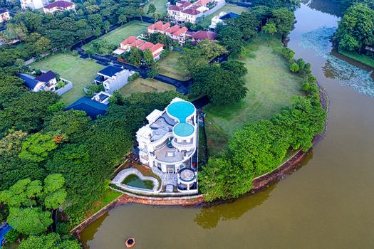 Drone shot of a lakeside mansion surrounded by lush greenery in South Tangerang, Indonesia.