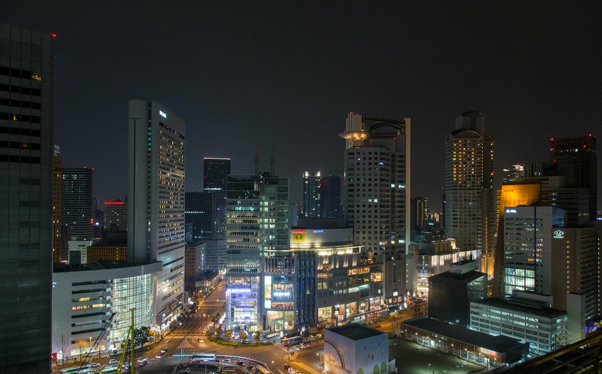 Stunning view of Osaka's modern skyline at night with brightly lit buildings and vibrant city lights.