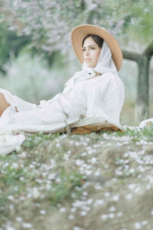 Free Woman in White Dress Sitting on Grass Field Stock Photo