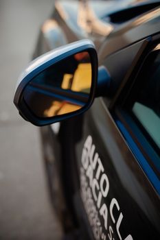 Detailed view of a car's side mirror reflecting a blurred background.