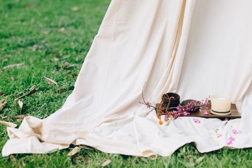 Free A serene outdoor setup featuring a candle, pink flowers, and fabric on a grassy lawn. Stock Photo