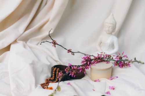 Free A tranquil setup with a Buddha statue, flowers, and meditation items, ideal for mindfulness and relaxation themes. Stock Photo