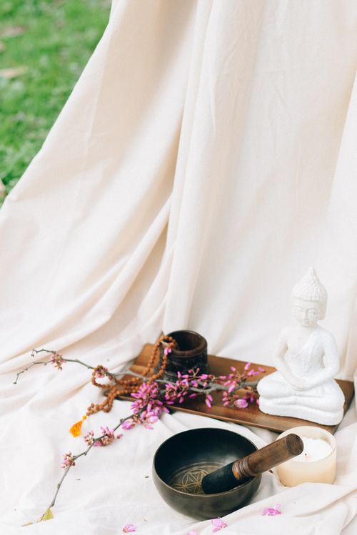 Free Tranquil meditation scene featuring Buddha statue, Tibetan singing bowl, and flowers. Stock Photo