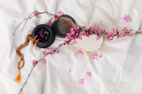 Free Elegant still life displaying pink flowers, wooden containers, and a bead necklace on fabric. Ideal for relaxation themes. Stock Photo
