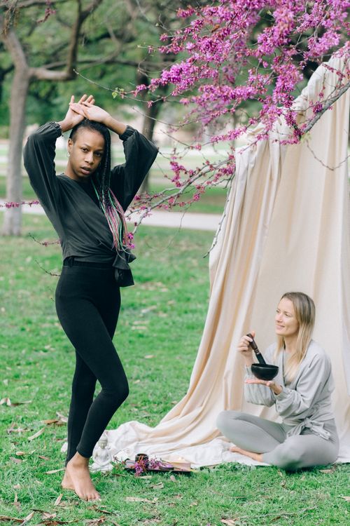 Free Two women engaging in a wellness session outdoors with a Tibetan singing bowl and yoga poses. Stock Photo