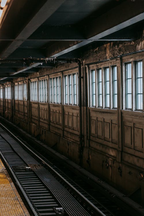 Aged subway station with empty rails and shabby walls with windows and pipes in city