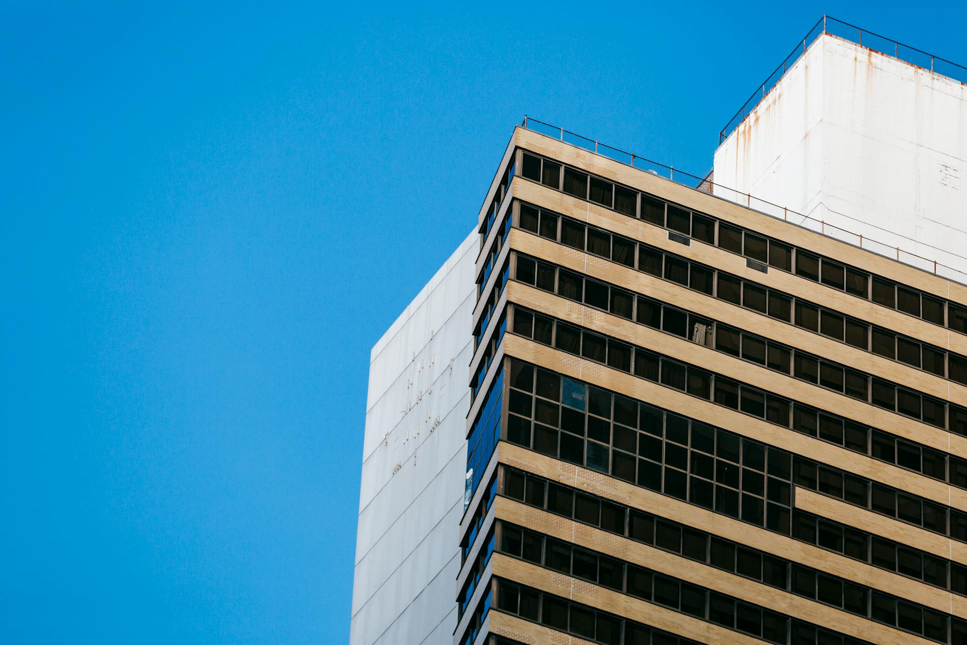 From below of contemporary multistory buildings against bright blue sky on sunny day in city