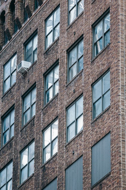 Low angle of symmetric windows of modern residential brick building locate din city in daytime