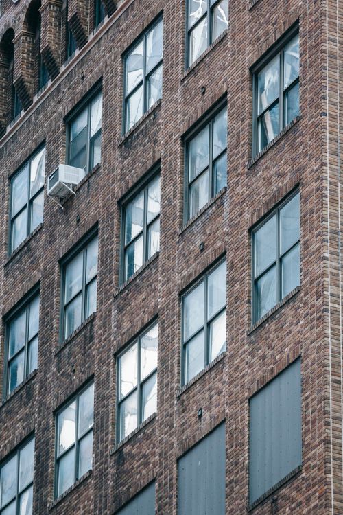 Free Low angle of symmetric windows of modern residential brick building locate din city in daytime Stock Photo