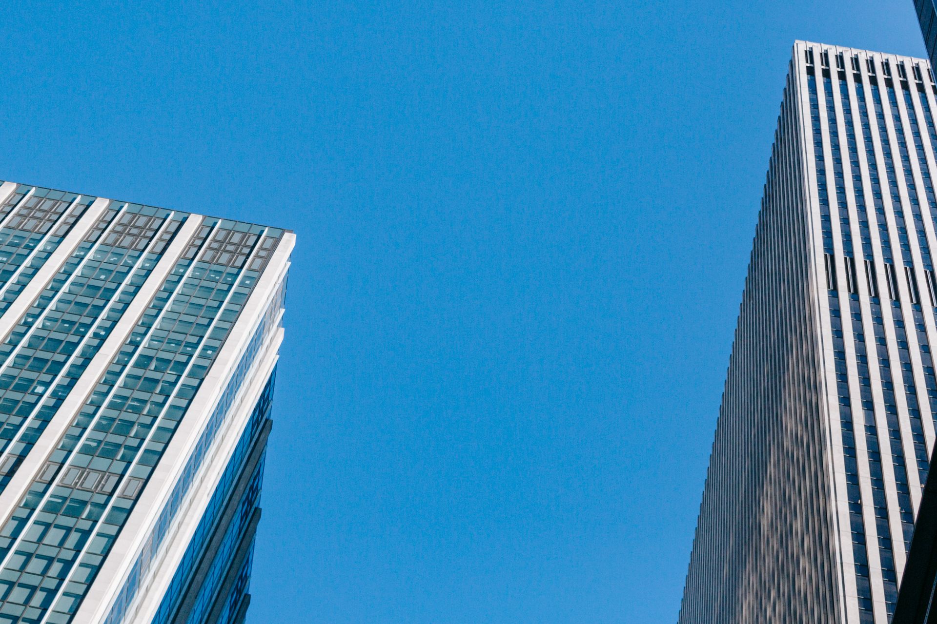 From below of modern business centers under bright blue cloudless sky in daytime