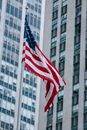 From below national US flag waving on pole against modern skyscraper in urban city district