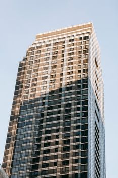 From below of contemporary high building exterior with shadow under light sky in town in sunlight
