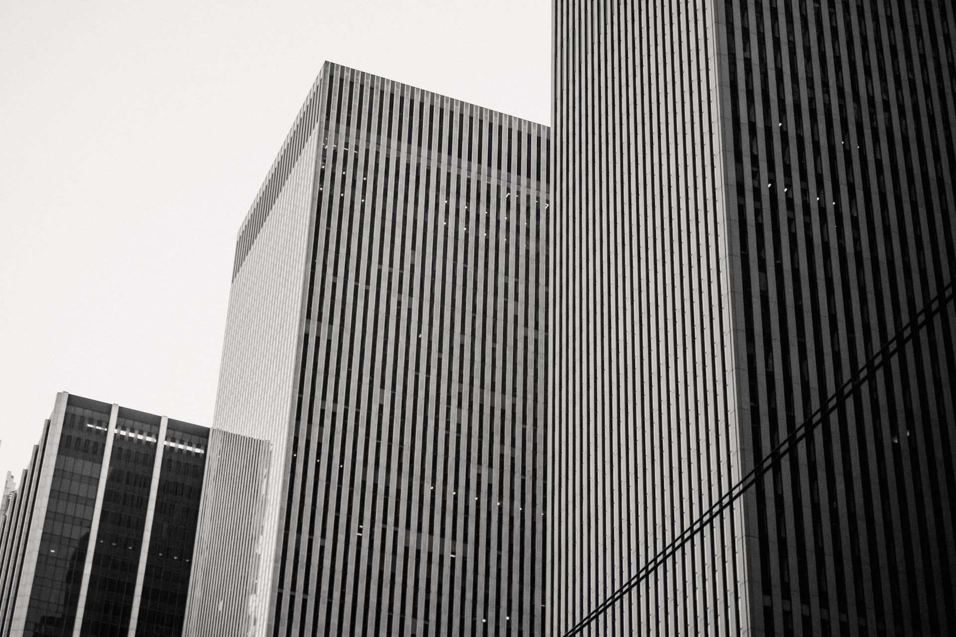 From below black and white of modern urban multistory building exteriors in row in daylight