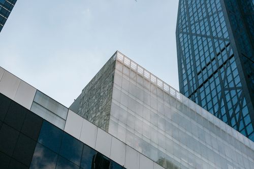 Free From below of contemporary multistory building exteriors with geometric walls reflecting cloudy sky in town Stock Photo