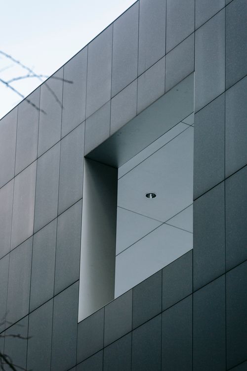 Free Contemporary multistory house exterior with gray wall and square shaped window reflecting light sky in city Stock Photo