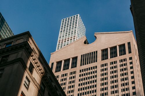 Free Low angle of modern skyscraper and aged building exteriors with ornament and shades in sunny city Stock Photo