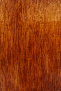 Backdrop of brown wooden wall with wavy lines and blots on varnished surface with dense texture